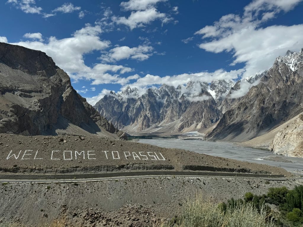 Breathtaking view of the Passu Cones with a welcoming sign, showcasing stunning mountainous landscape in Pakistan.